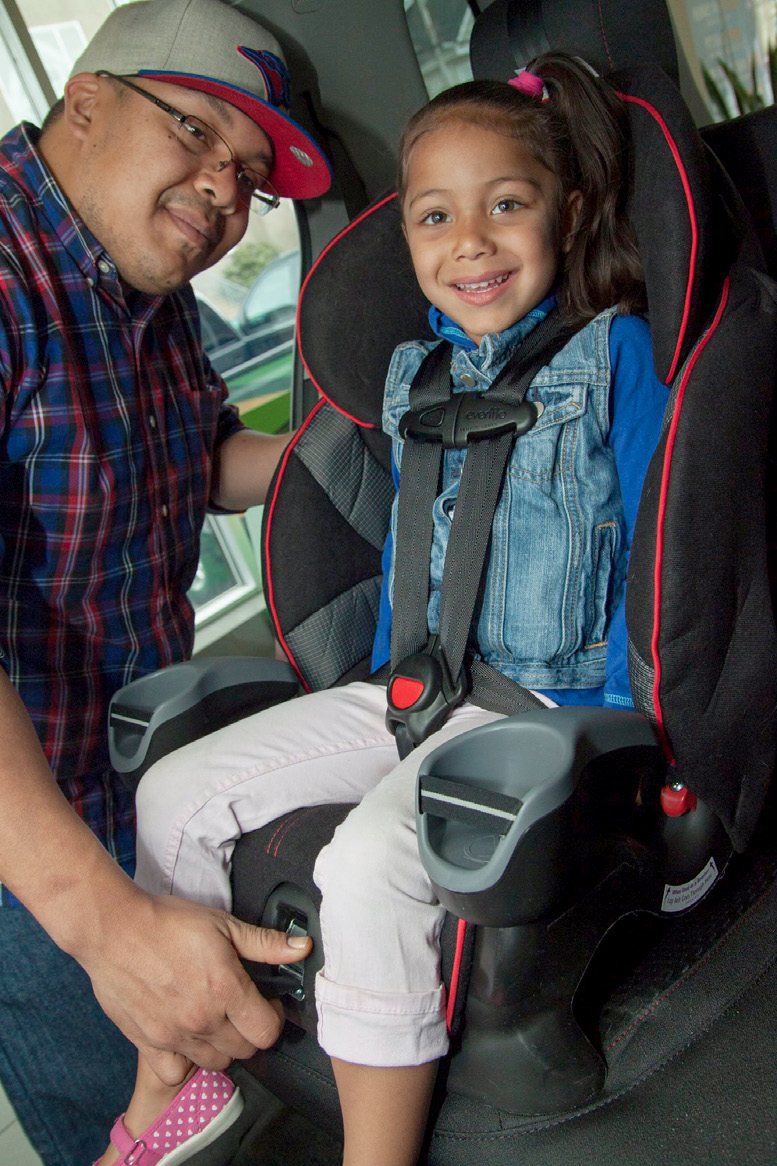 Older child buckled into a car seat with a 5-point harness, facing the front of the car.