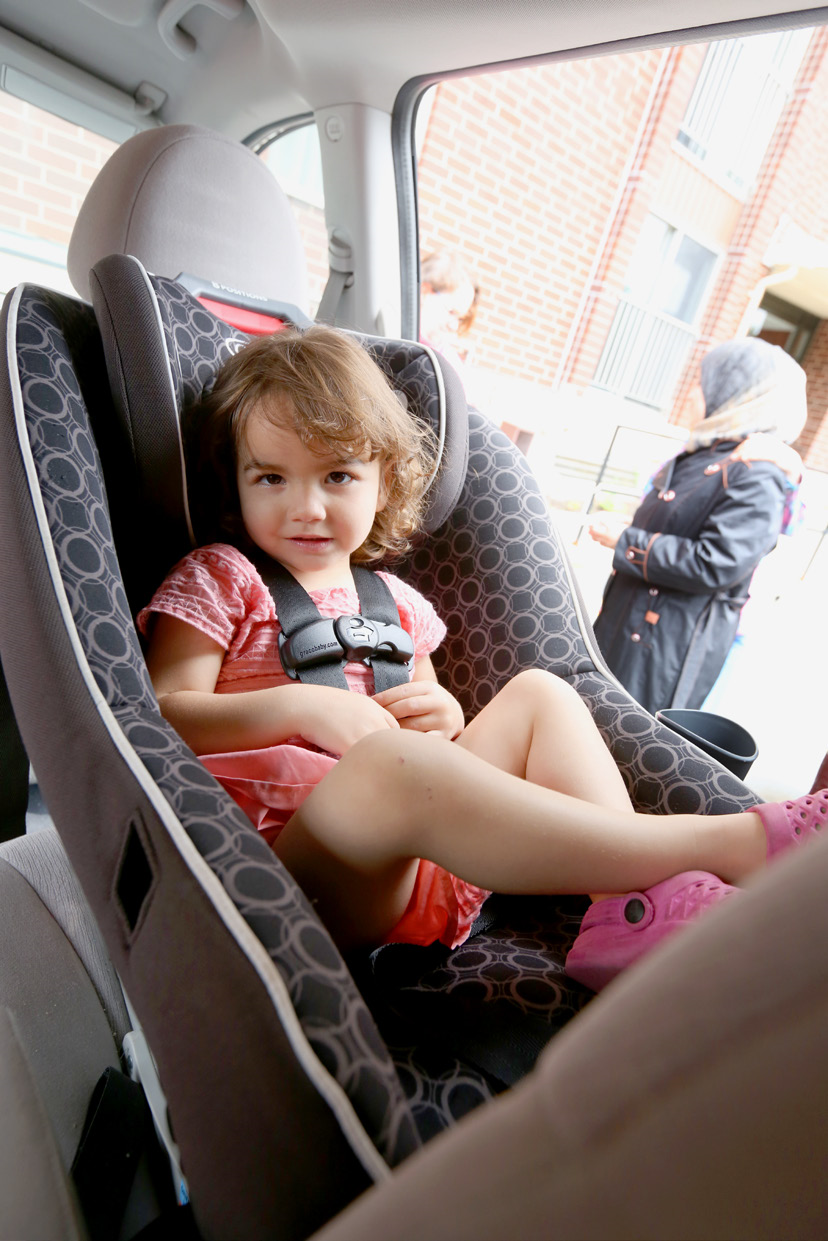 Baby buckled into a car seat facing the back of the car.