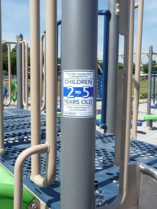 Label on playground equipment pole showing recommended age.