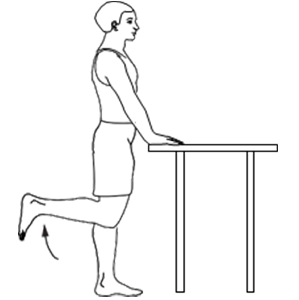 Person standing holding onto counter for support, bending 1 knee by lifting their heel towards their buttocks.