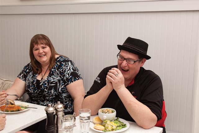 2 people laughing while eating together.