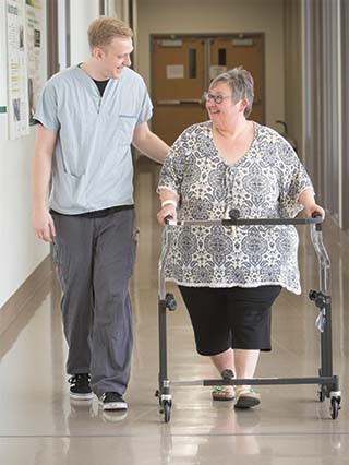 Healthcare provider and patient walking down a hallway.
