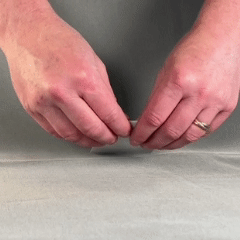 Close up of 2 hands pinching paper and ripping it. Hands do the same movement, but in different directions.