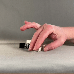 Close up of a hand picking up an interlocking brick and turning it to fit another interlocking brick.